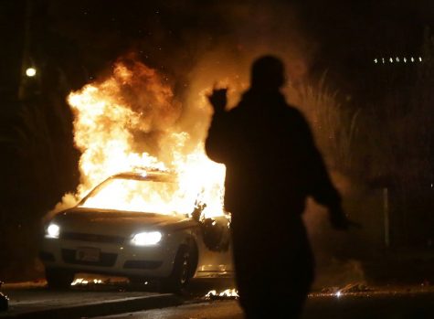 A protester watches a police car burn after the announcement of the grand jury decision not to indict police officer Darren Wilson in the fatal shooting of Michael Brown, an unarmed black 18-year-old, Monday, Nov. 24, 2014, in Ferguson, Mo. (AP Photo/Charlie Riedel)