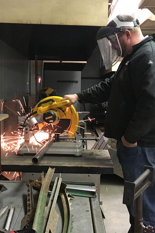Teacher Nathan Howard cuts a piece of metal. The metal not used will be available for someone else to use.